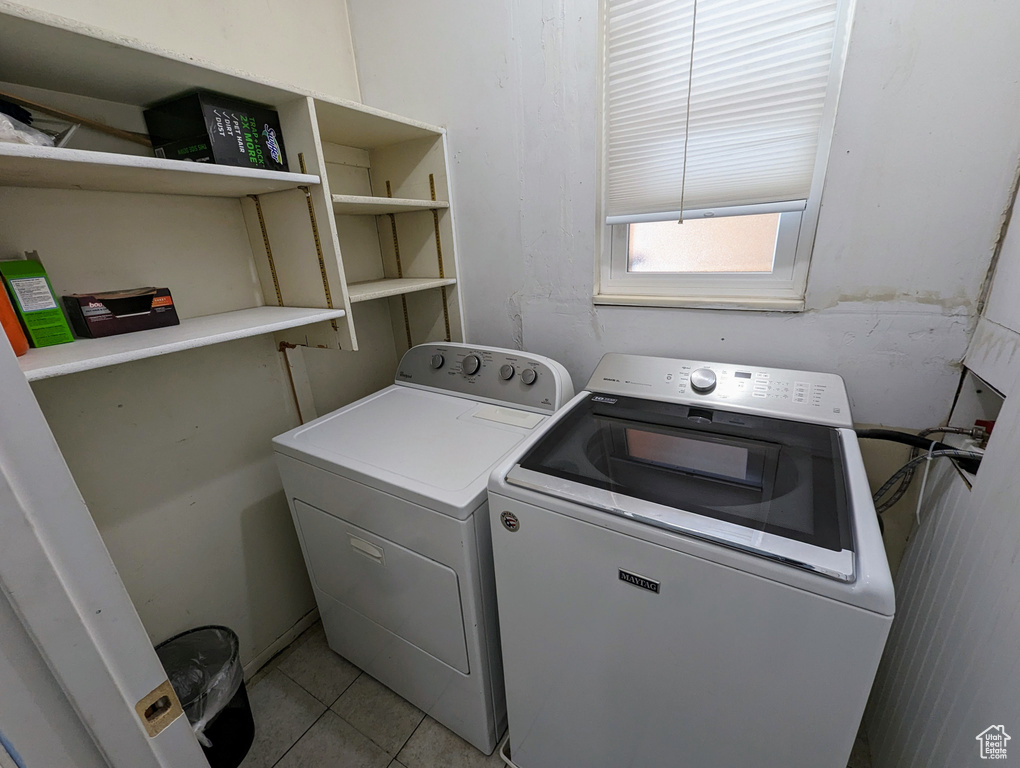 Washroom featuring light tile flooring and washing machine and dryer