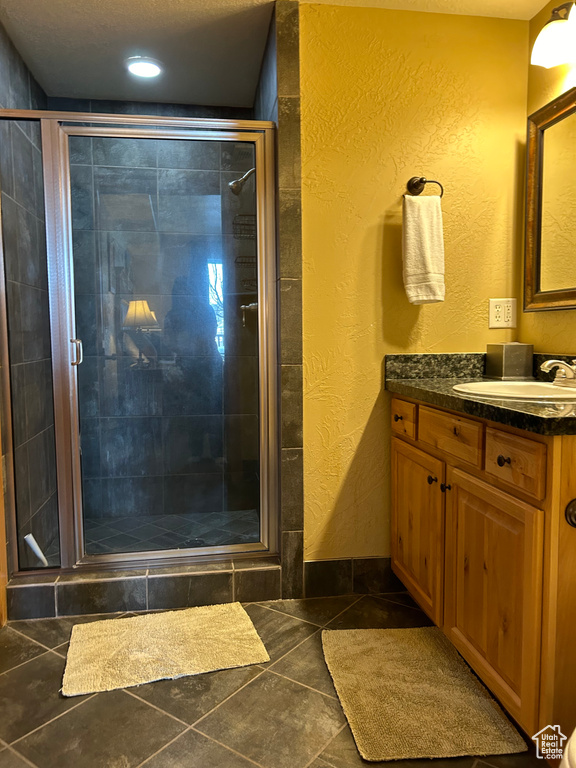 Bathroom featuring tile flooring, vanity, and a shower with door