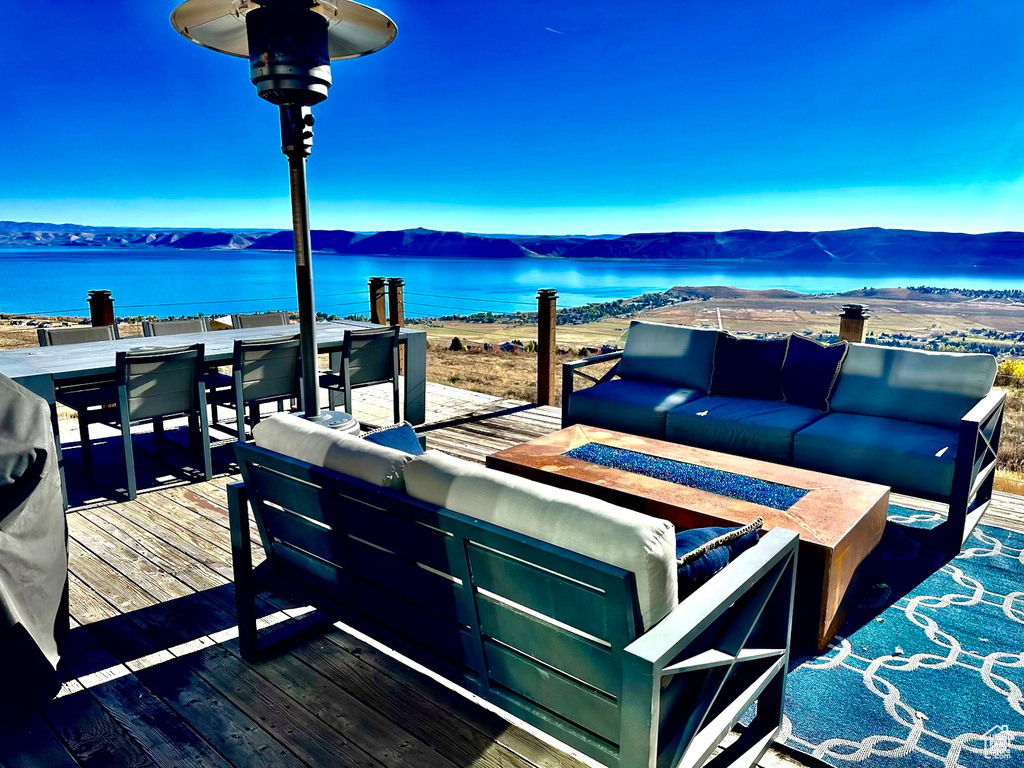 View of patio featuring an outdoor living space with a fire pit and a deck with water view