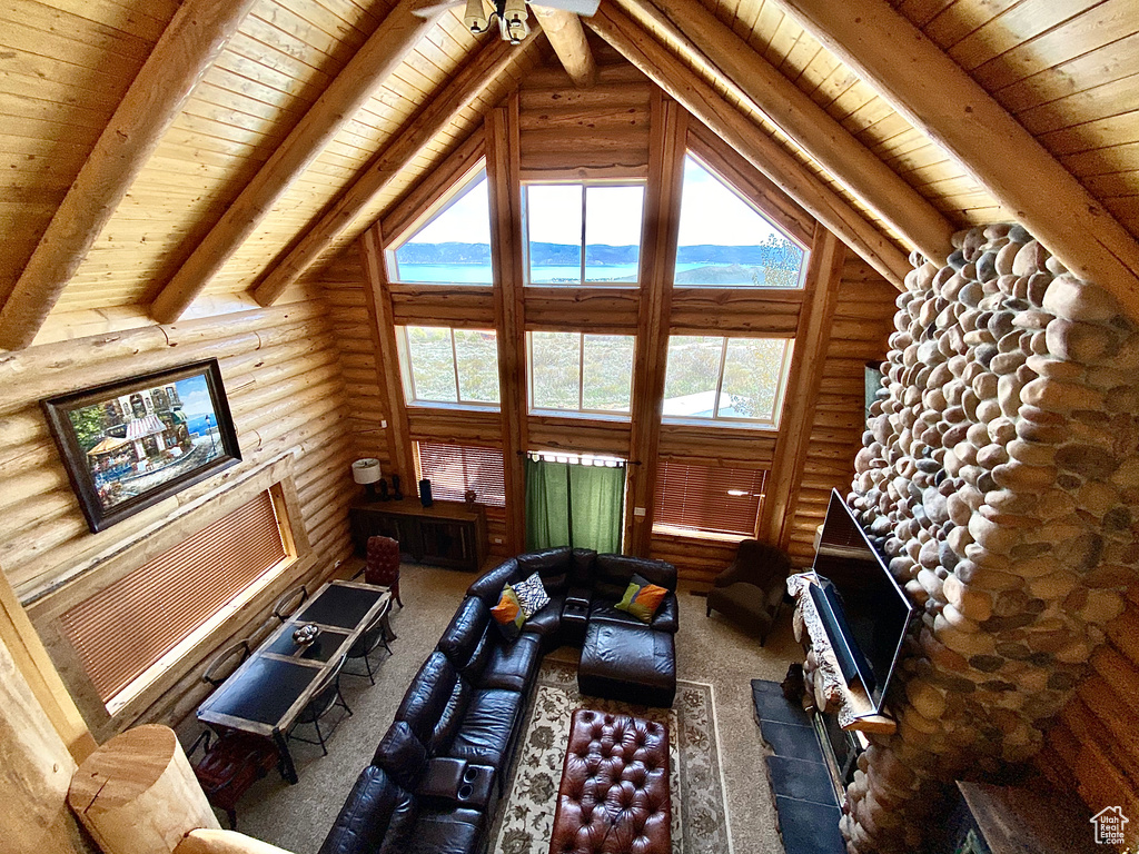 Carpeted living room featuring log walls, high vaulted ceiling, wooden ceiling, and ceiling fan