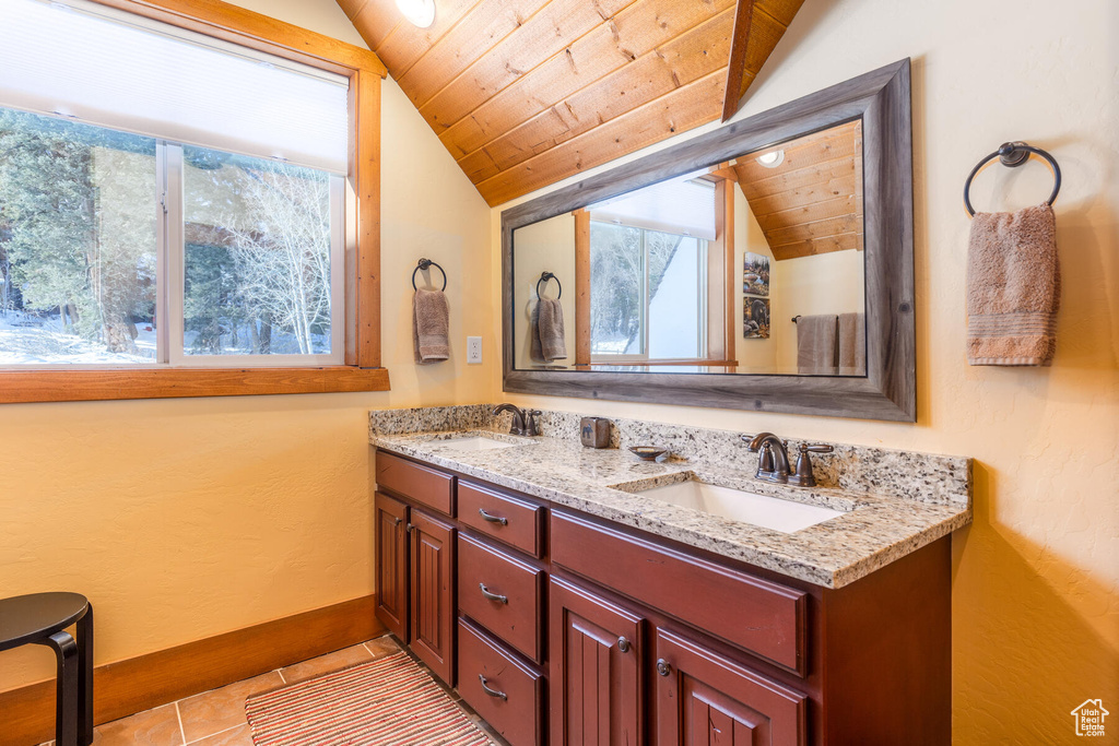Bathroom with vaulted ceiling, wood ceiling, tile flooring, and dual vanity