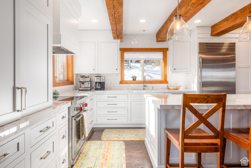 Kitchen featuring tasteful backsplash, white cabinets, hanging light fixtures, and premium appliances