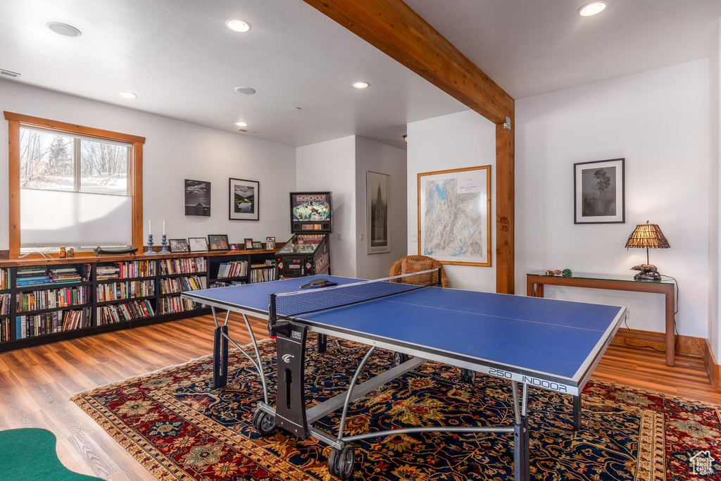 Recreation room with wood-type flooring and beam ceiling