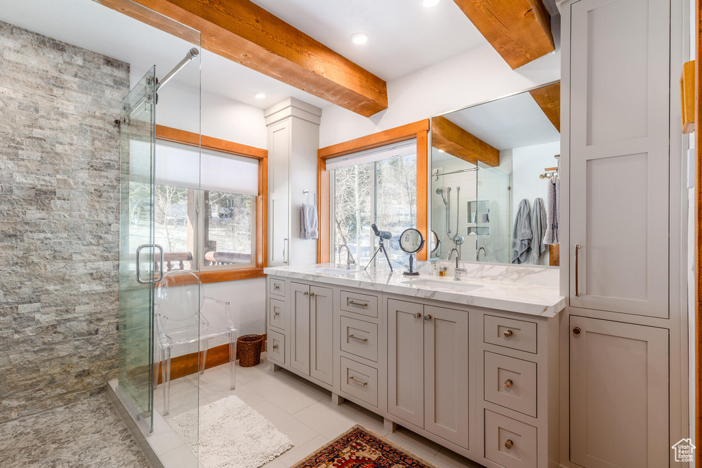 Bathroom with oversized vanity, dual sinks, a shower with door, tile floors, and beamed ceiling