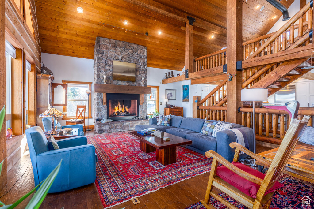 Living room featuring a stone fireplace, beam ceiling, wood ceiling, high vaulted ceiling, and dark wood-type flooring