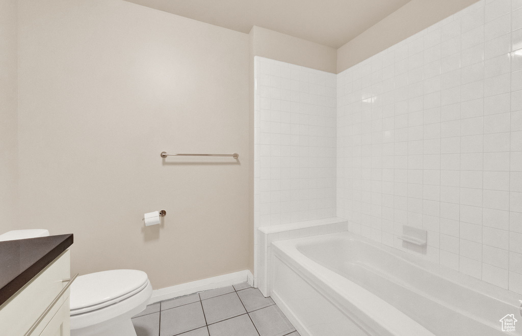 Full bathroom featuring vanity, tiled shower / bath combo, toilet, and tile flooring
