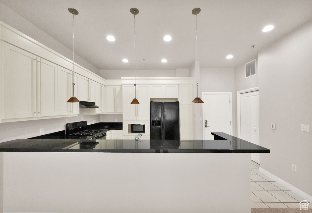 Kitchen with hanging light fixtures, white cabinets, light tile flooring, and black appliances