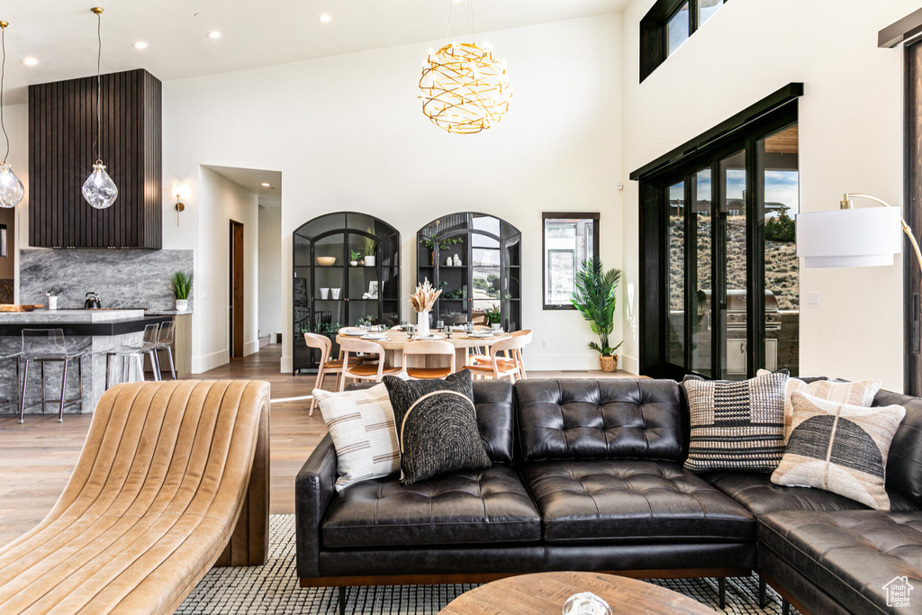 Living room with a notable chandelier, light wood-type flooring, and high vaulted ceiling