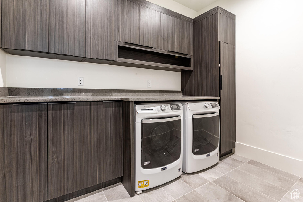 Laundry room with cabinets, washer and dryer, and light tile flooring