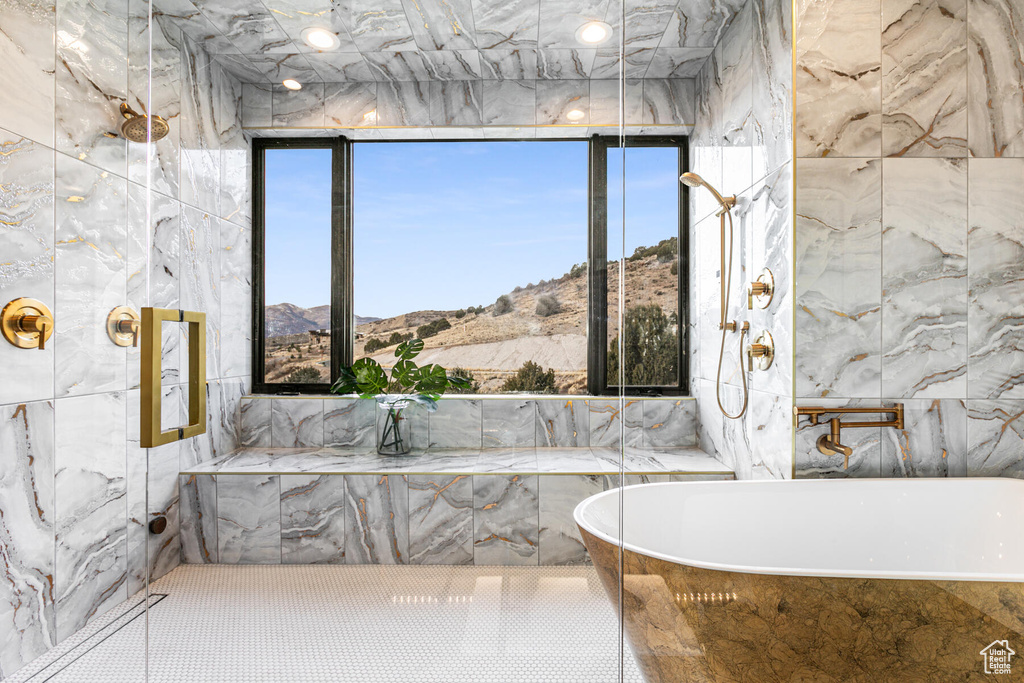 Bathroom featuring tiled tub, a mountain view, and tile walls