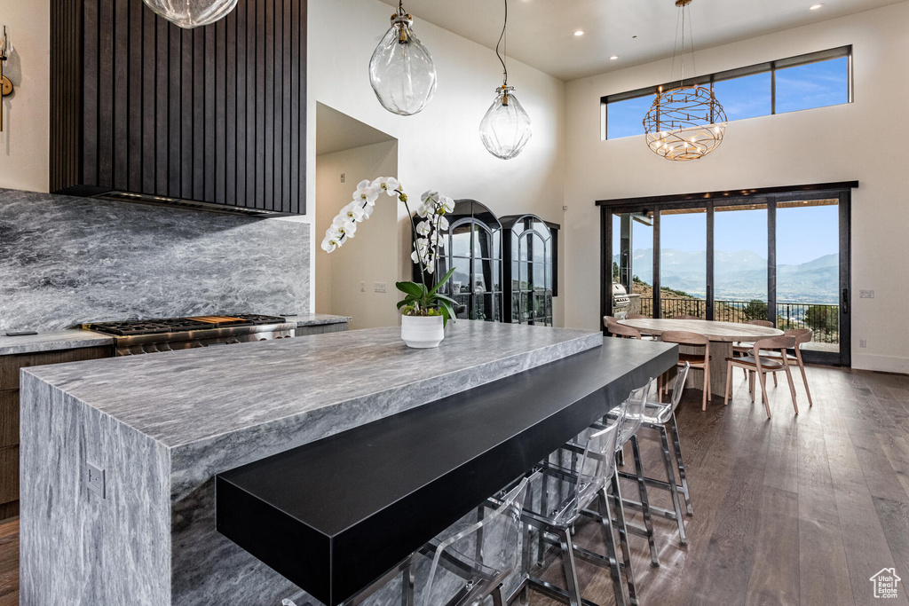 Kitchen featuring dark wood-type flooring, a breakfast bar, and hanging light fixtures