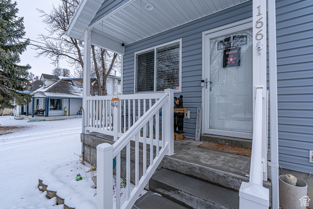 Snow covered property entrance with covered porch