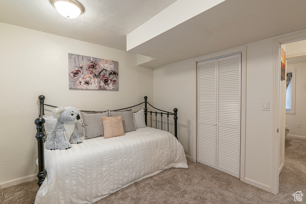 Bedroom featuring light colored carpet, a closet, and a textured ceiling