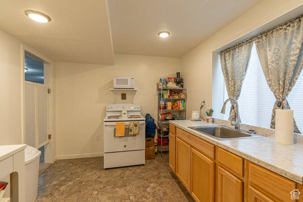 Kitchen with dark tile flooring, white appliances, and sink