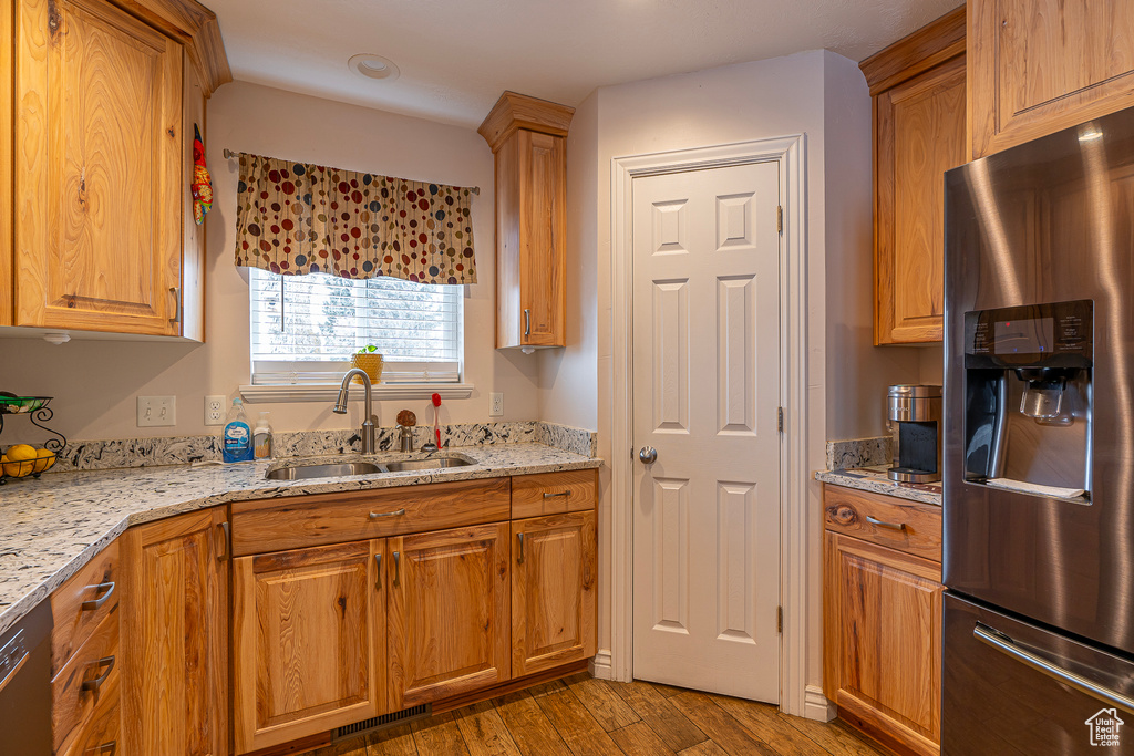 Kitchen featuring dark hardwood / wood-style floors, stainless steel fridge with ice dispenser, light stone countertops, and sink