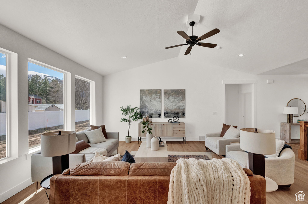 Living room with lofted ceiling, light hardwood / wood-style floors, and ceiling fan