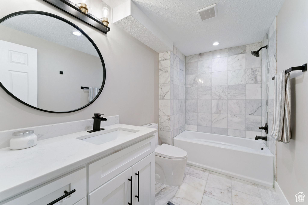 Full bathroom with tile floors, tiled shower / bath, toilet, and vanity