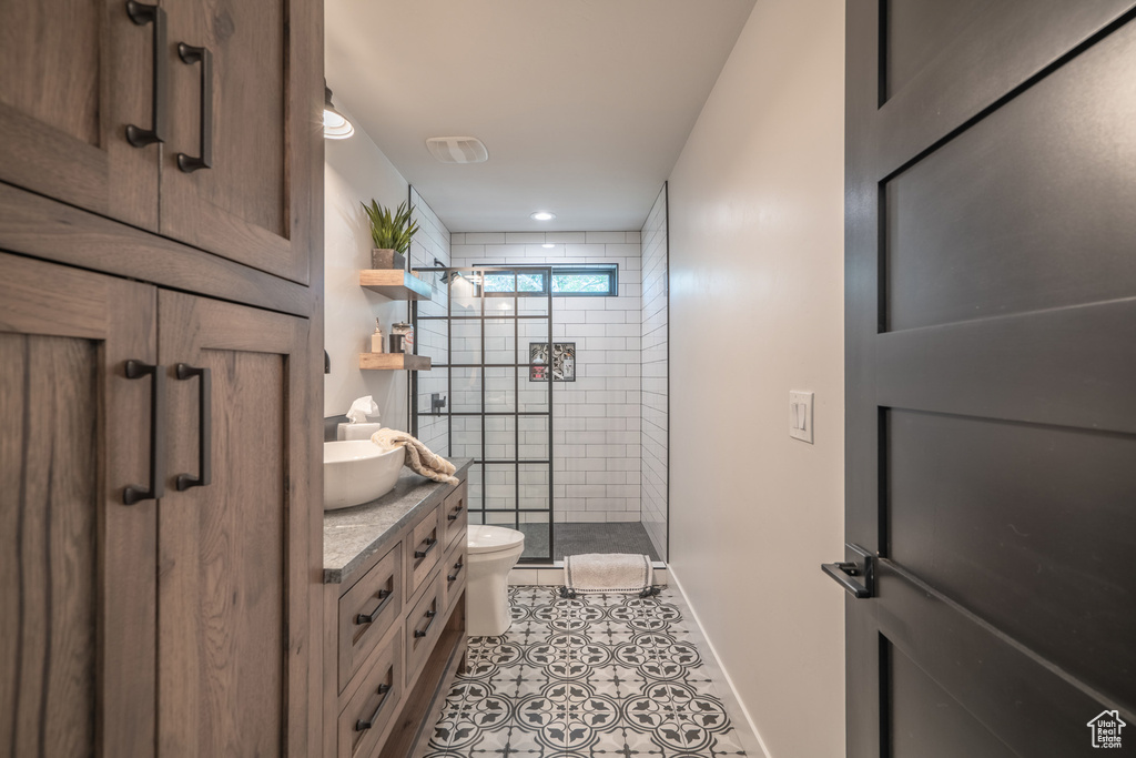Bathroom featuring tile floors, vanity, toilet, and tiled shower