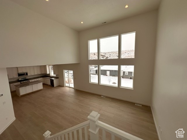 Unfurnished living room featuring hardwood / wood-style floors and a wealth of natural light