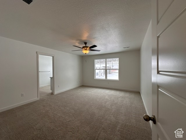 Empty room featuring carpet floors, a textured ceiling, and ceiling fan