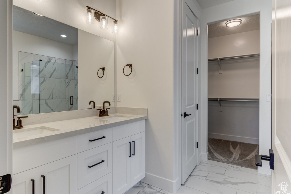 Bathroom featuring double sink vanity, tile floors, and a shower with door