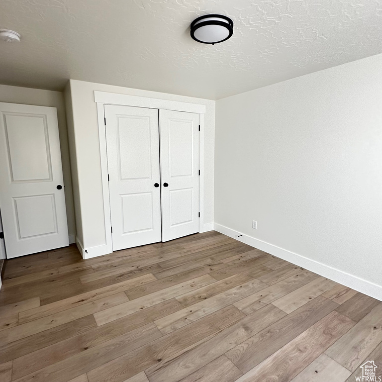Unfurnished bedroom featuring dark hardwood / wood-style floors, a closet, and a textured ceiling
