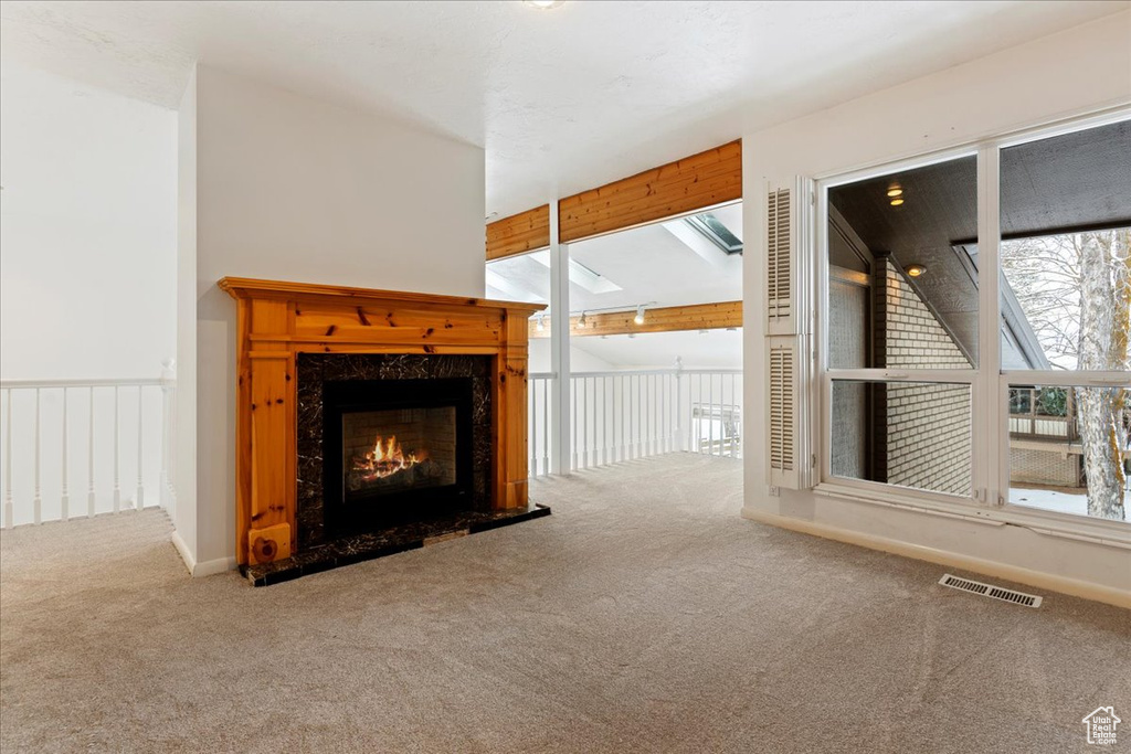 Unfurnished living room with light colored carpet, a fireplace, and lofted ceiling with beams