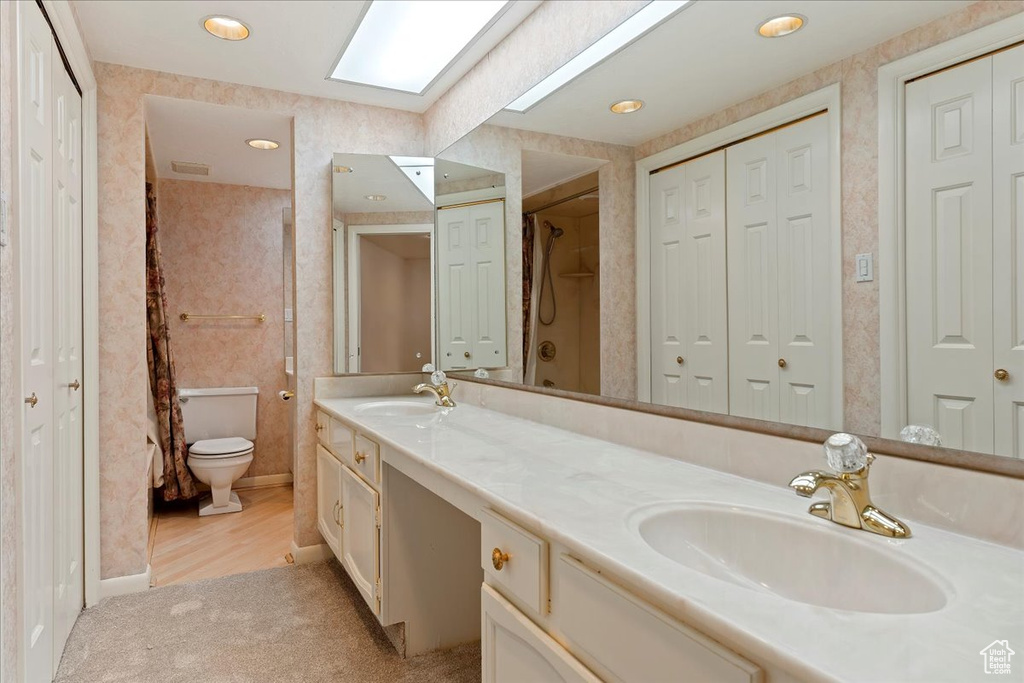 Bathroom with double vanity, toilet, and hardwood / wood-style flooring