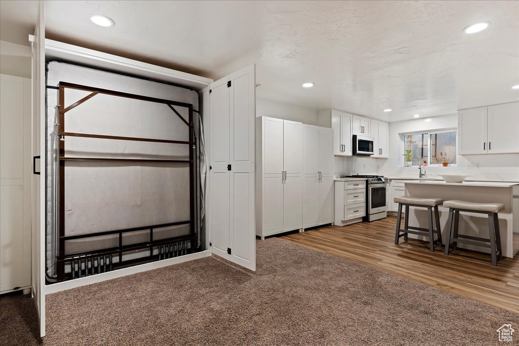 Interior space featuring stainless steel appliances, light hardwood / wood-style floors, white cabinets, and a kitchen bar