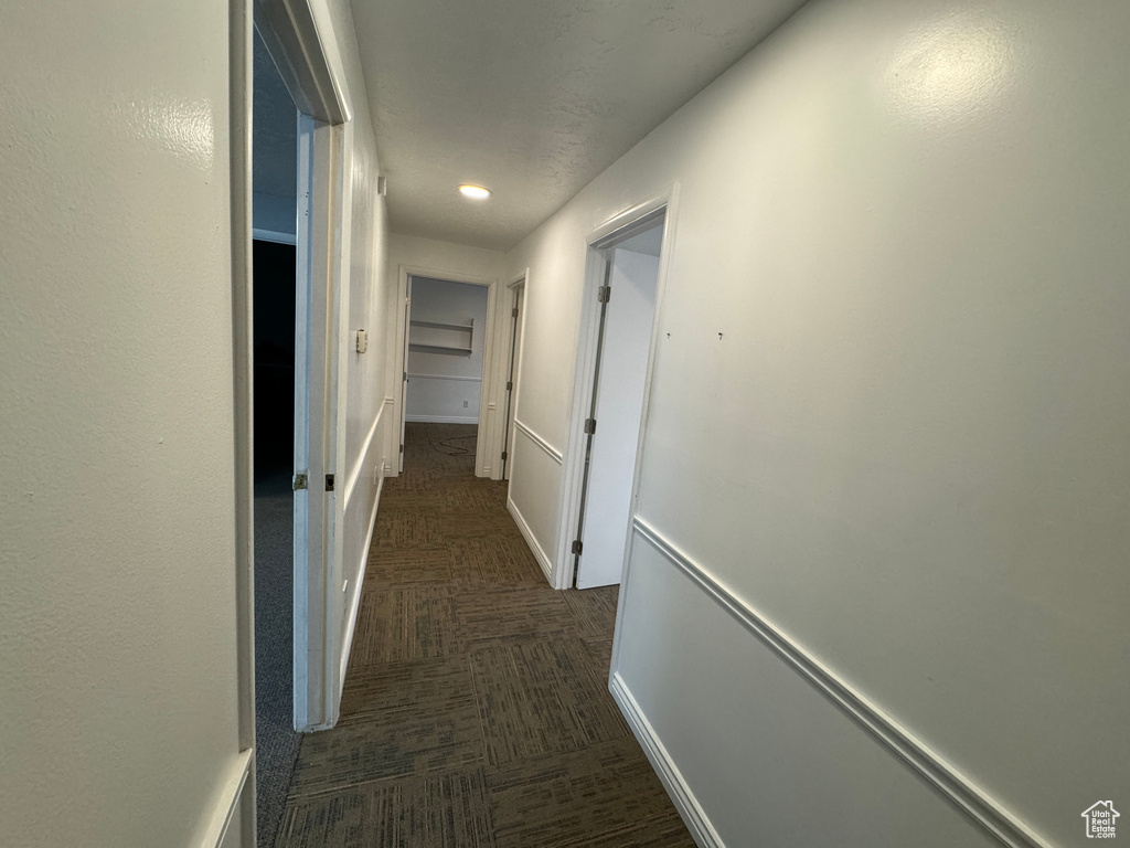Corridor featuring dark colored carpet