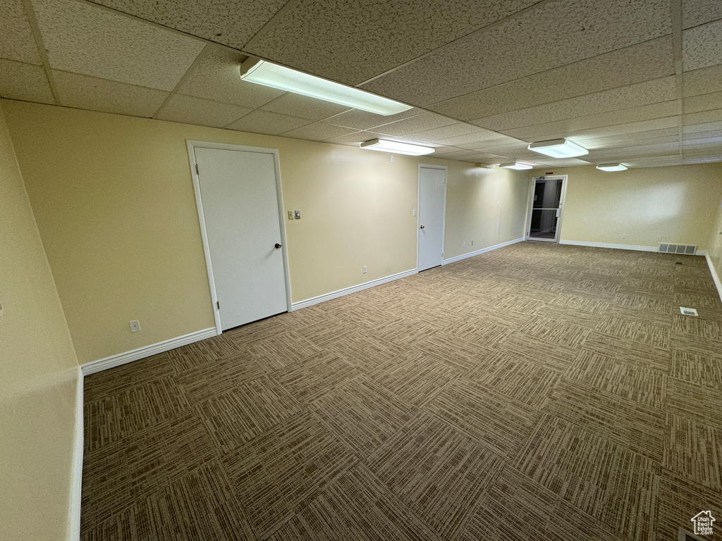 Basement featuring a drop ceiling and dark colored carpet