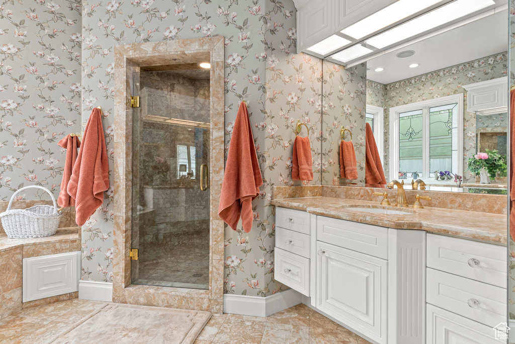 Bathroom with tile floors, vanity with extensive cabinet space, and a shower with door