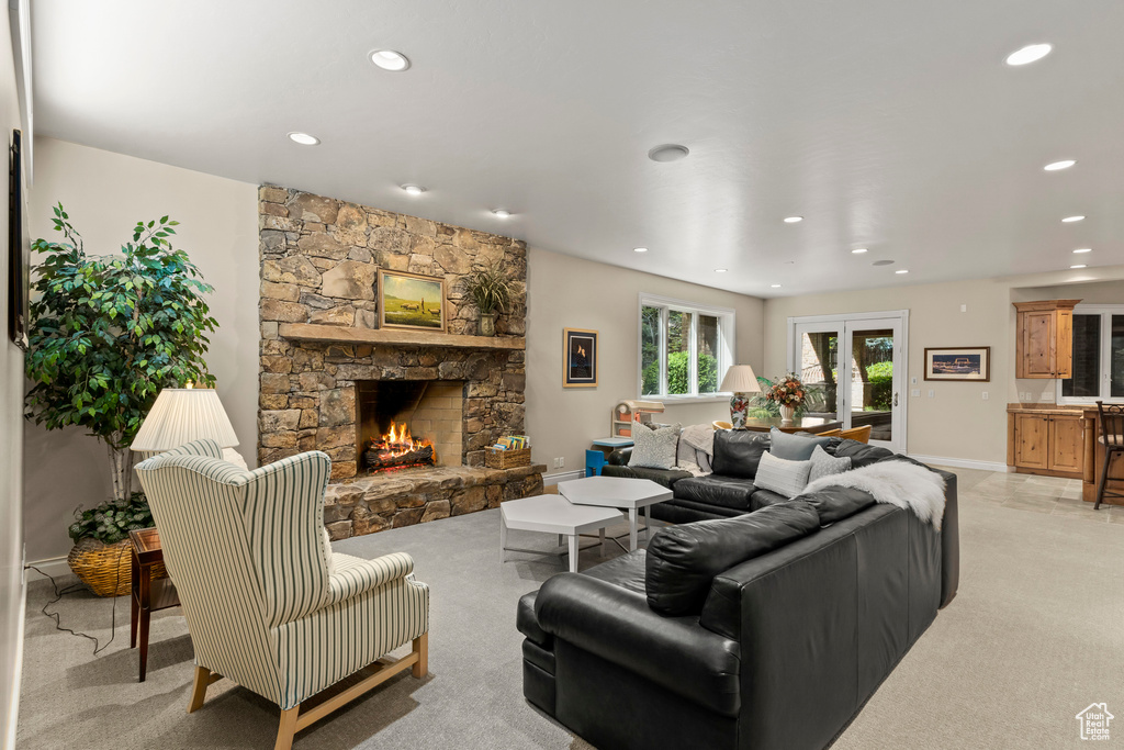Living room featuring a stone fireplace, french doors, and light colored carpet