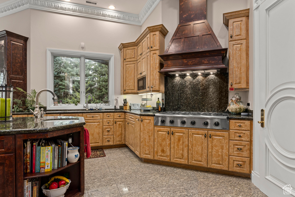 Kitchen with crown molding, stainless steel gas cooktop, light tile floors, tasteful backsplash, and custom exhaust hood