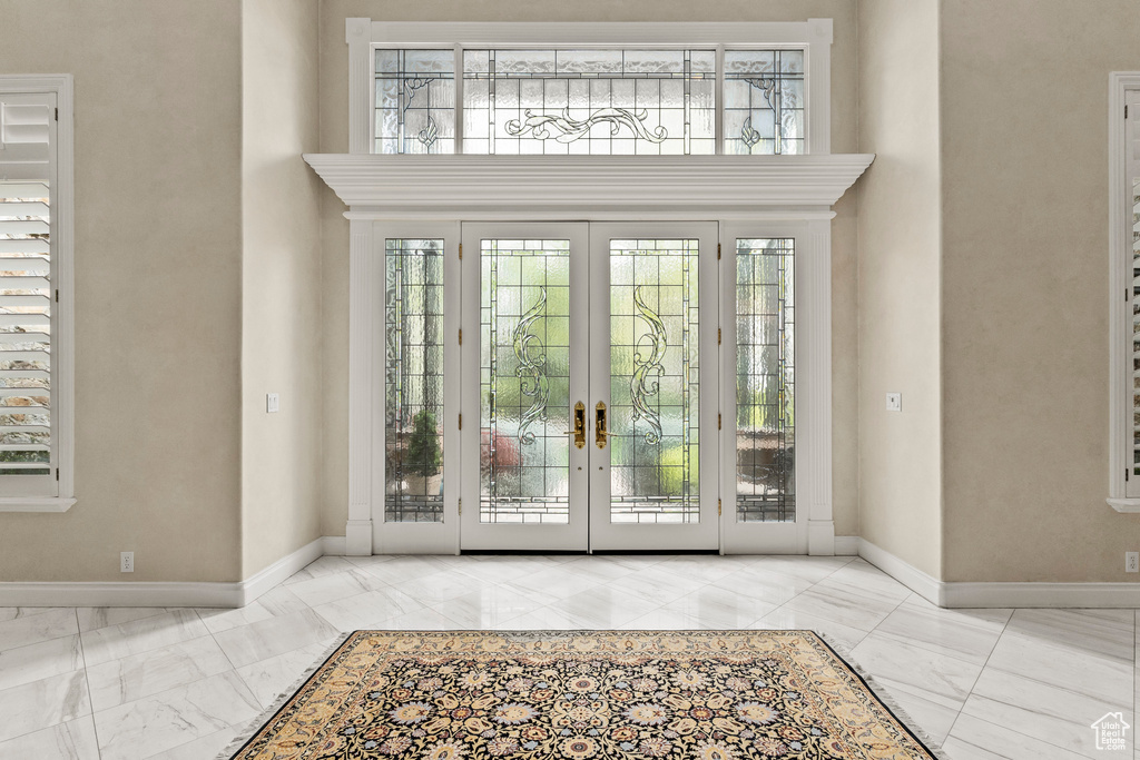 Doorway with french doors, a towering ceiling, and light tile floors