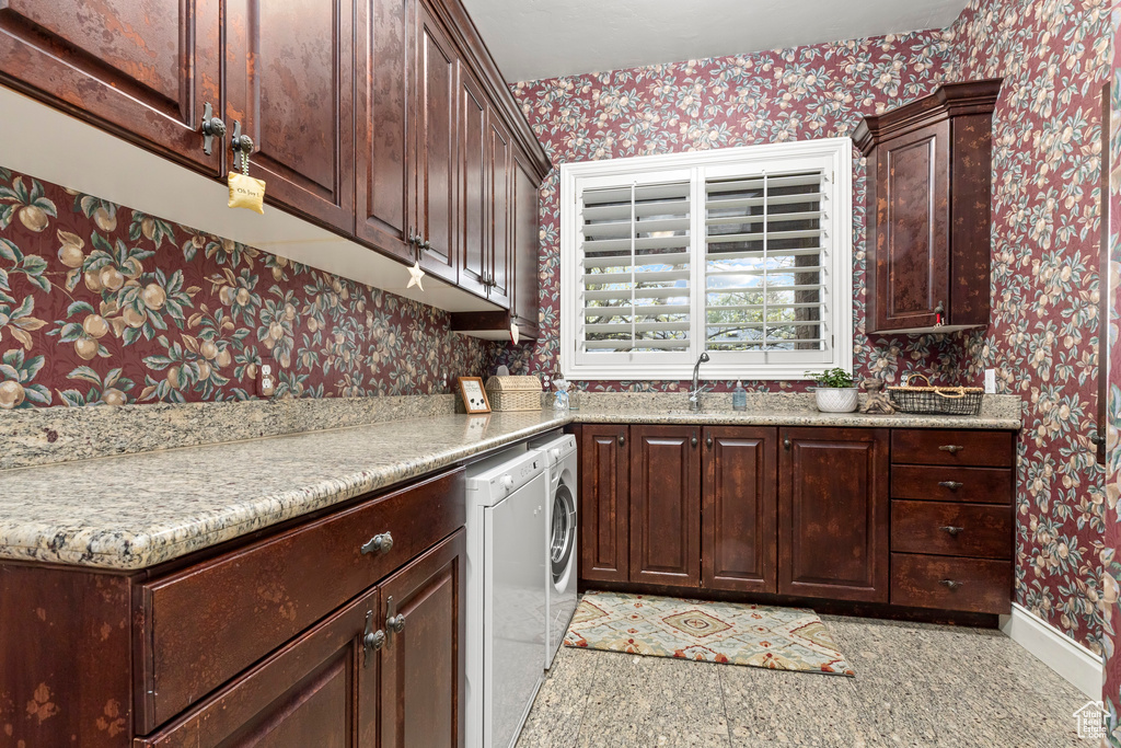 Kitchen featuring washing machine and clothes dryer, sink, light tile flooring, and dark brown cabinetry
