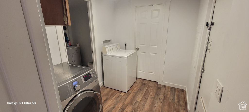 Laundry room with washing machine and clothes dryer, dark hardwood / wood-style floors, and cabinets