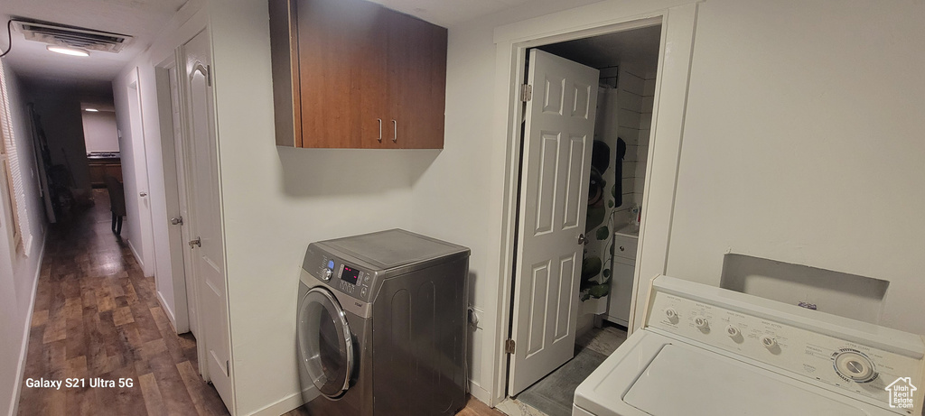 Washroom featuring washer / clothes dryer, cabinets, and dark wood-type flooring