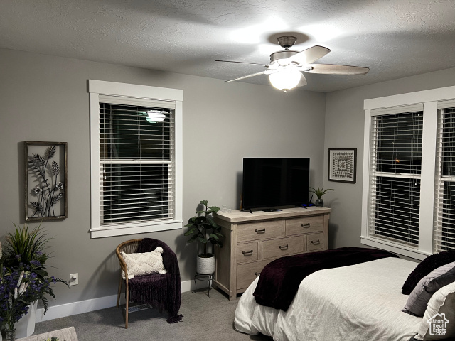 Carpeted bedroom featuring a textured ceiling and ceiling fan
