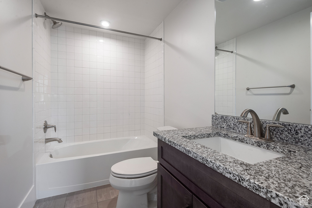Full bathroom with tiled shower / bath, toilet, large vanity, and tile flooring