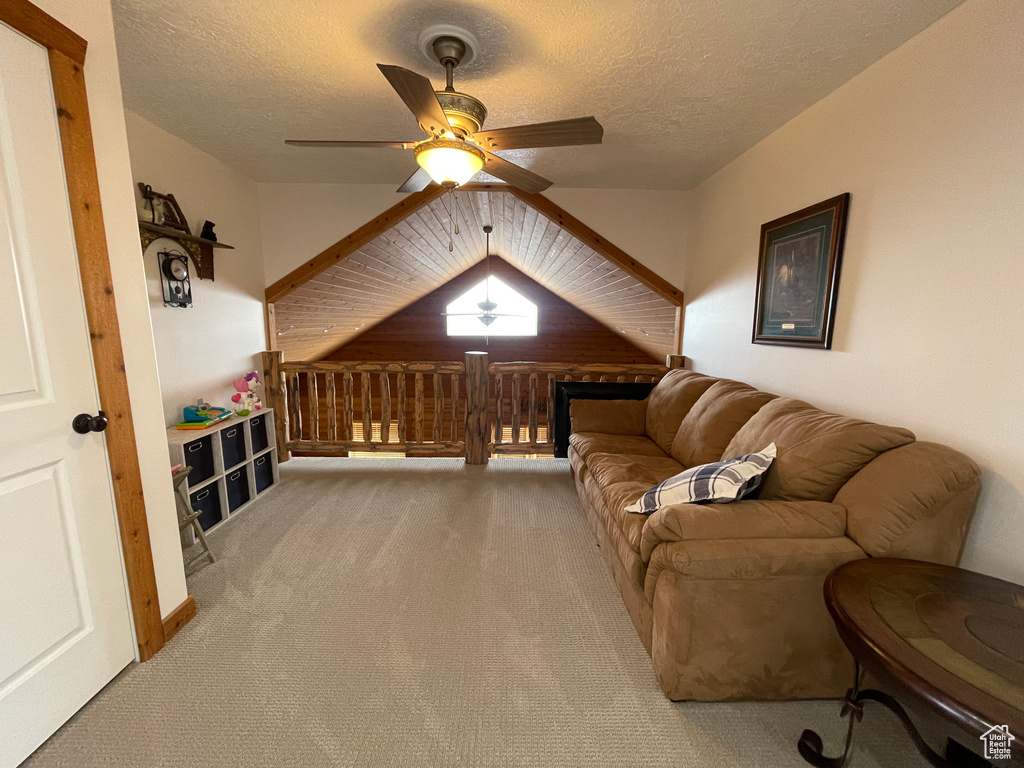 Interior space with vaulted ceiling, light colored carpet, a textured ceiling, and ceiling fan