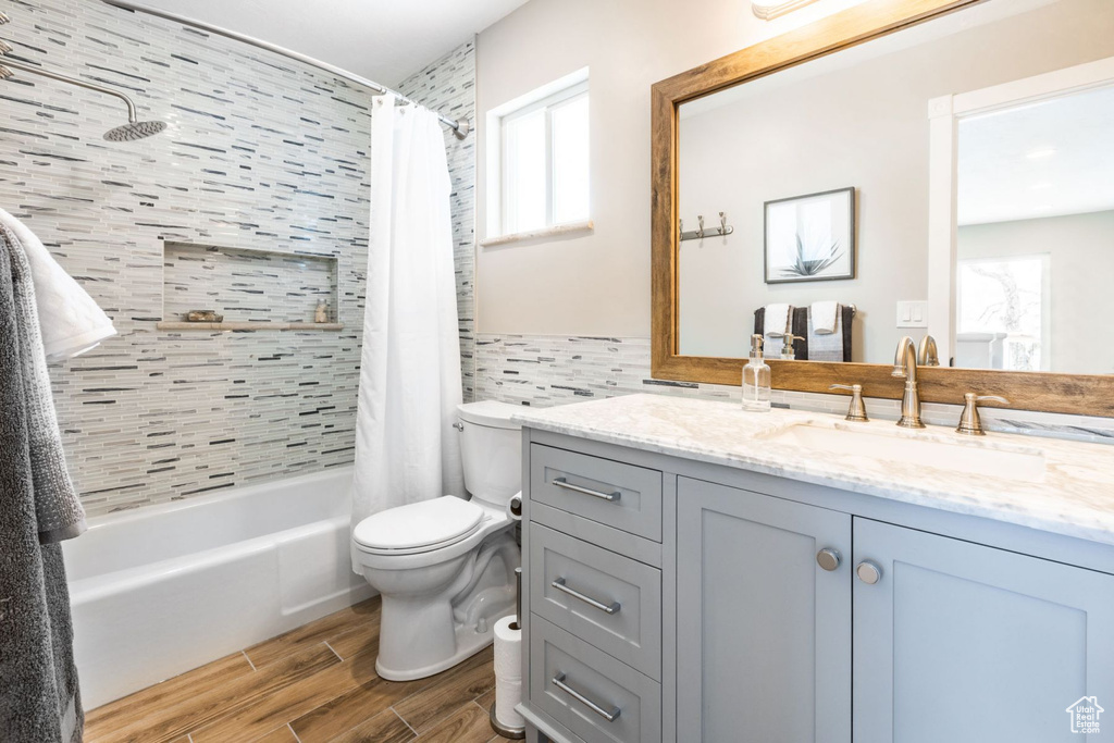 Full bathroom featuring a wealth of natural light, large vanity, shower / bath combo with shower curtain, and toilet