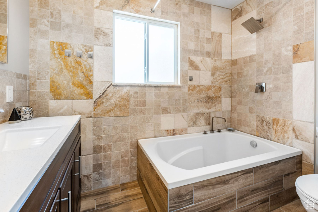 Full bathroom featuring tub / shower combination, toilet, vanity, and tile walls