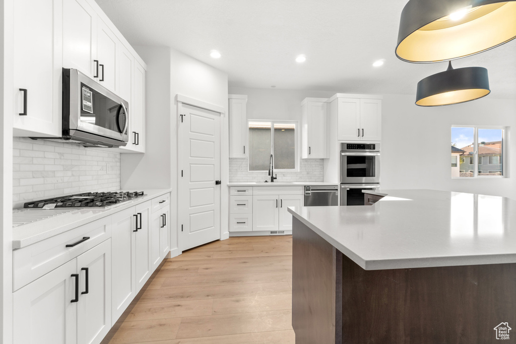 Kitchen with sink, tasteful backsplash, appliances with stainless steel finishes, and light wood-type flooring