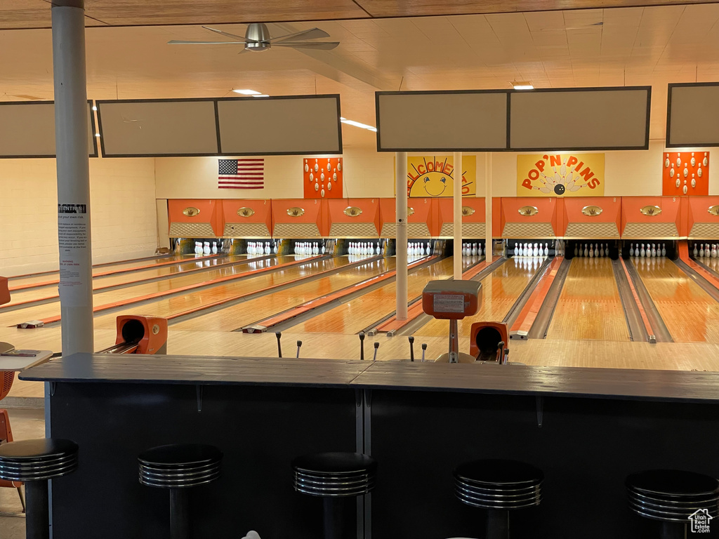 Bar with gray cabinets, a bowling alley, and ceiling fan