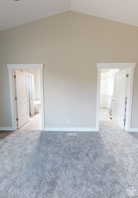 Unfurnished room with light colored carpet and lofted ceiling