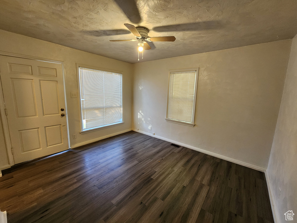 Spare room with dark wood-type flooring and ceiling fan