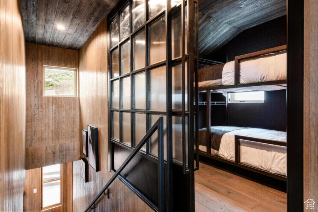 Bedroom with wooden walls, vaulted ceiling, light wood-type flooring, and wooden ceiling