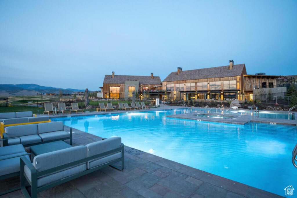 Pool at dusk featuring a patio area and an outdoor hangout area