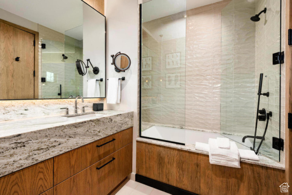 Bathroom with bath / shower combo with glass door, tile floors, and large vanity